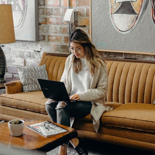 a woman sitting on a couch and typing
